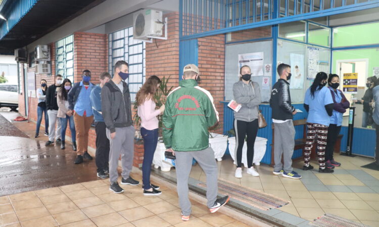 JOVENS FAZEM FILA PARA SE VACINAR CONTRA A COVID-19